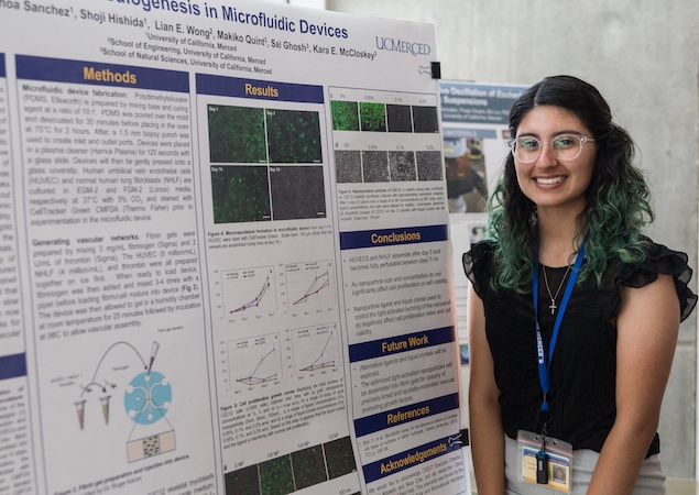 Student stands in front of scientific poster at a research symposium.
